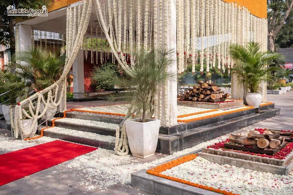 Green Park Shamshan Ghat cremation platform decorated by Last Ride Funeral with jasmine garland curtains, marigold and rose petal arrangements, sandalwood pyre and red carpet — a dignified farewell setup